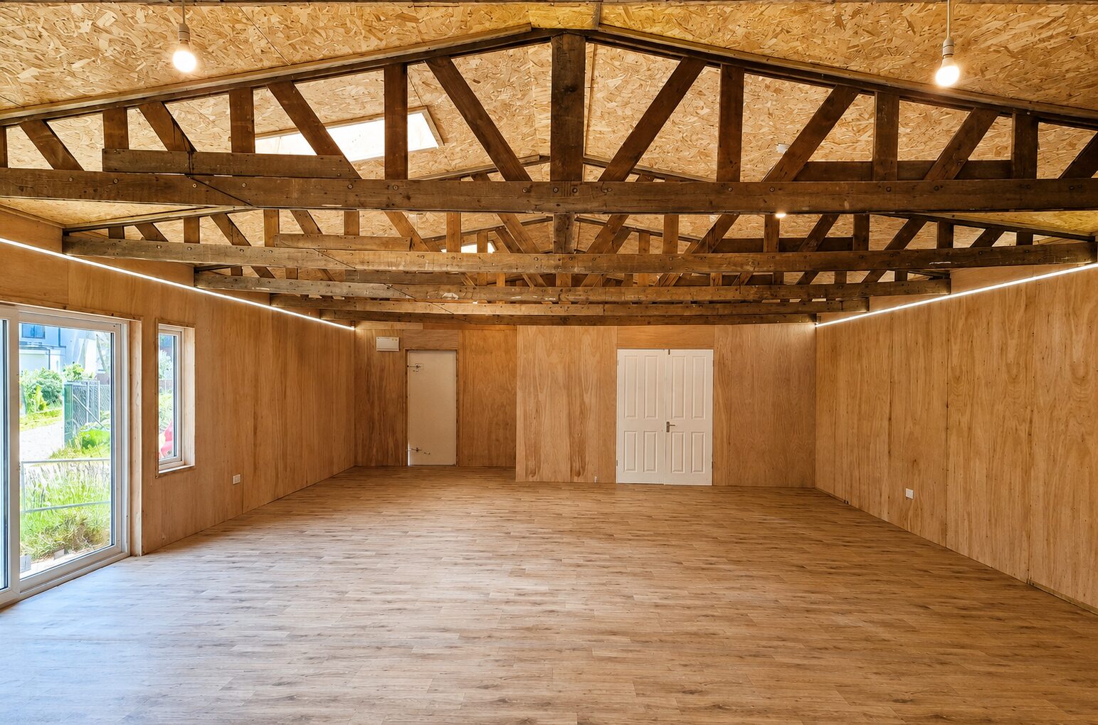 Completed open-plan garden building interior with timber trusses